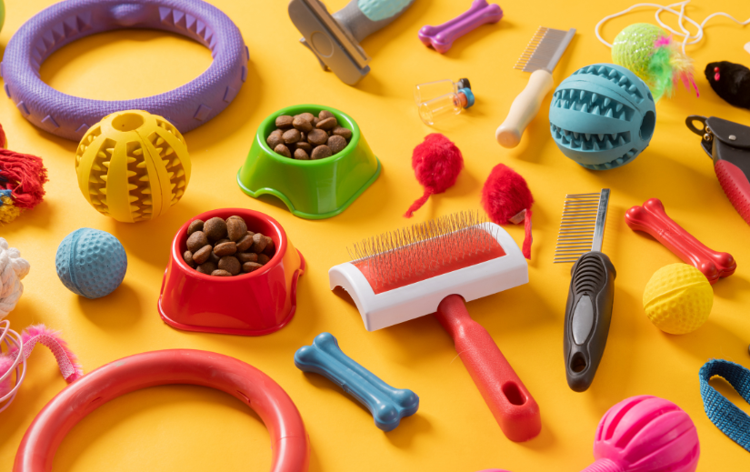 Variety of pet supplies for dropshipping niche, including toys, brushes, and food bowls on a yellow background.